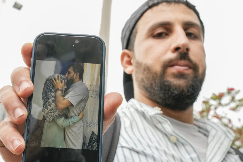 Kassem Abo Zeed holds up a phone displaying a photo of himself with his wife, Ezra, who is missing after a fishing boat carrying migrants sank off southern Greece, in the southern port city of Kalamata on Thursday, June 15, 2023. Abo Zeed traveled from Hamburg, Germany to try and find his wife and her missing brother, Abdullah Aoun. (AP Photo/Thanassis Stavrakis)