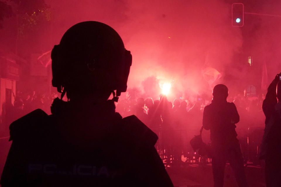 Demonstrators hold up flares next to the police officers during a protest against the amnesty at the headquarters of Socialist party in Madrid, Spain, Thursday, Nov. 16, 2023. Spain's acting Socialist prime minister, Pedro Sánchez, has been chosen by a majority of legislators to form a new leftist coalition government in a parliamentary vote. The vote came after nearly two days of debate among party leaders that centered almost entirely on a highly controversial amnesty deal for Catalonia's separatists that Sánchez agreed to in return for vital support to get elected prime minister again. (AP Photo/Andrea Comas)