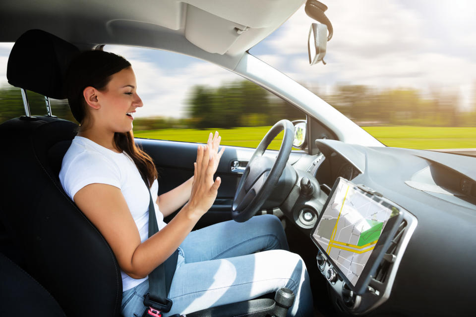 A woman taking her hands off the wheel of a driverless car