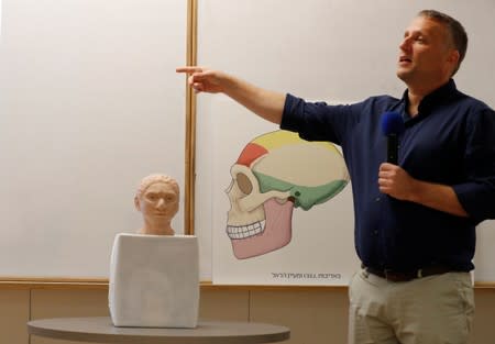 Hebrew University professor Liran Carmel, gestures next to the artistic rendering of the head and face of a 13-year-old girl from the the prehistoric human species, Denisovan, based on technology developed by Carmel and his team, in Jerusalem