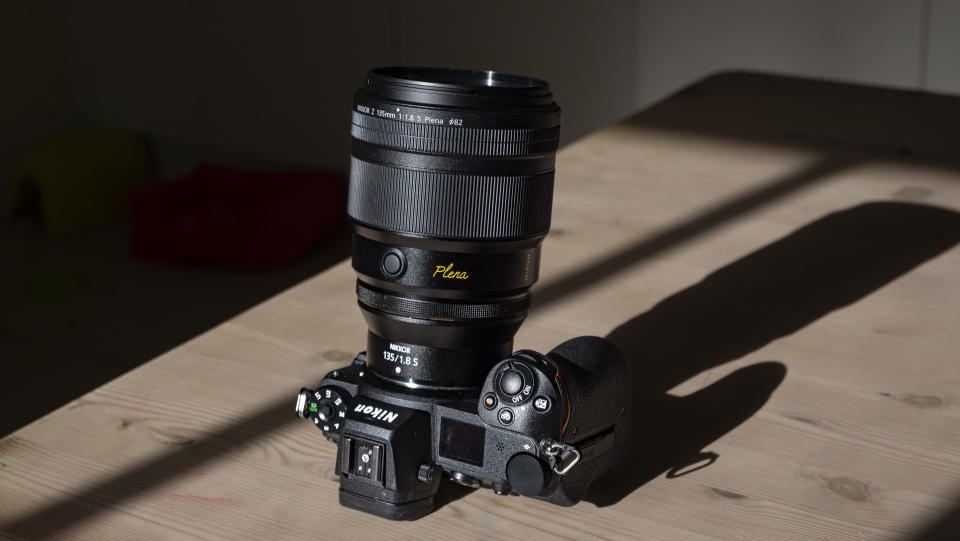 Nikon Z 135mm f/1.8 S Plena lens attached to a Z6 II on a wooden table in sunlight with shadow