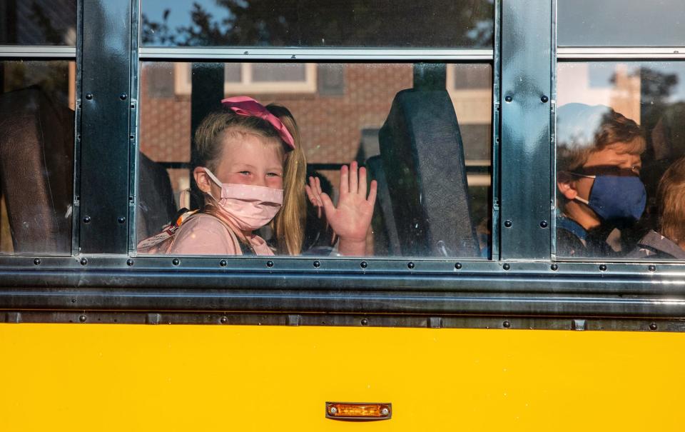 Harper Williams waves from the bus as she prepares for her first day of first grade at Sycamore Elementary School in Avon, Ind., on Wednesday, July 29, 2020.