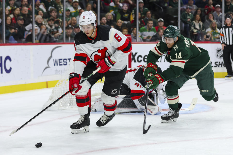 New Jersey Devils defenseman John Marino, left, skates with the puck alongside Minnesota Wild center Joel Eriksson Ek (14) during the first period of an NHL hockey game, Thursday, Nov. 2, 2023, in St. Paul, Minn. (AP Photo/Matt Krohn)