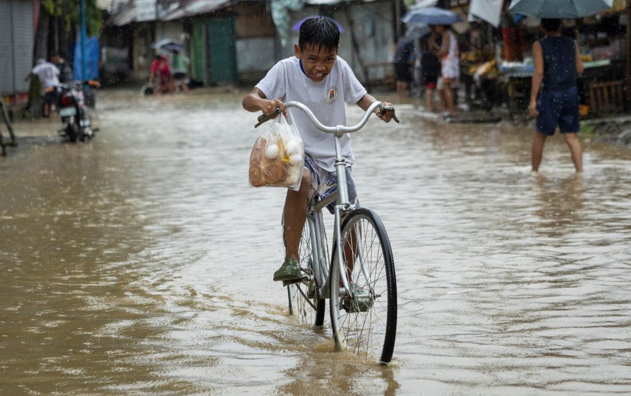 Boy cycles through flood waters