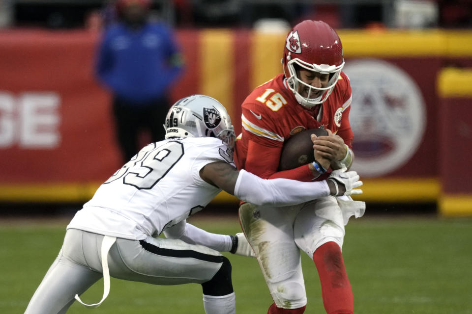 Kansas City Chiefs quarterback Patrick Mahomes (15) is stopped by Las Vegas Raiders cornerback Nate Hobbs (39) during the second half of an NFL football game Monday, Dec. 25, 2023, in Kansas City, Mo. (AP Photo/Charlie Riedel)