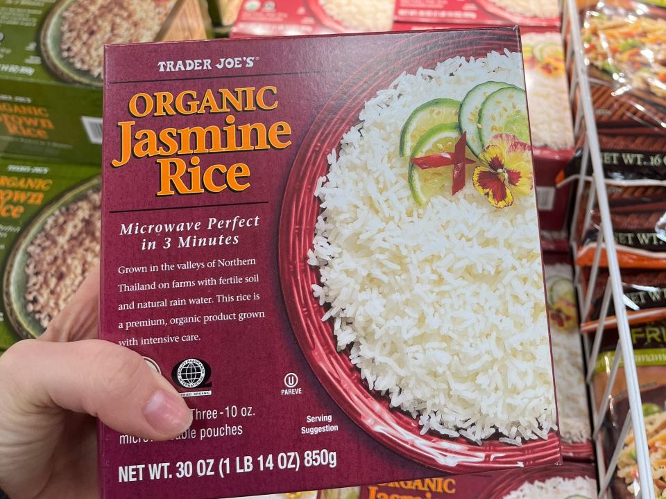 hand holding up a box of frozen organic jasmine rice at trader joes