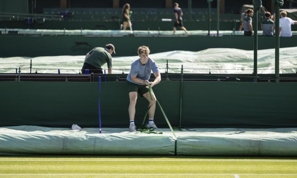 <span>Ground staff practising covering the lawn in case of rain on a championship court.</span><span>Photograph: Alessandro Della Valle/EPA</span>