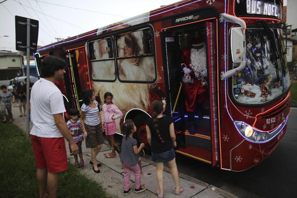 Bus driver Edilson, also known as "Fumassa", greets children as he wears a Santa Claus outfit inside an urban bus decorated with Christmas motives in Santo Andre