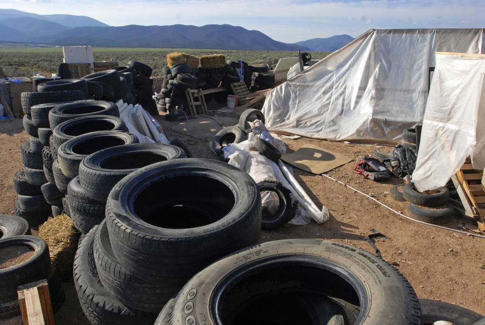 FILE - This Aug. 10, 2018 file photo shows a makeshift living compound in Amalia, N.M. Five former residents of a New Mexico compound where authorities found 11 hungry children and a dead 3-year-old boy are due in federal court on terrorism-related charges. The two men and three women living at the compound raided in August are being arraigned Thursday, March 21, 2019 on new charges of supporting plans for violent attacks. (AP Photo/Morgan Lee, File)