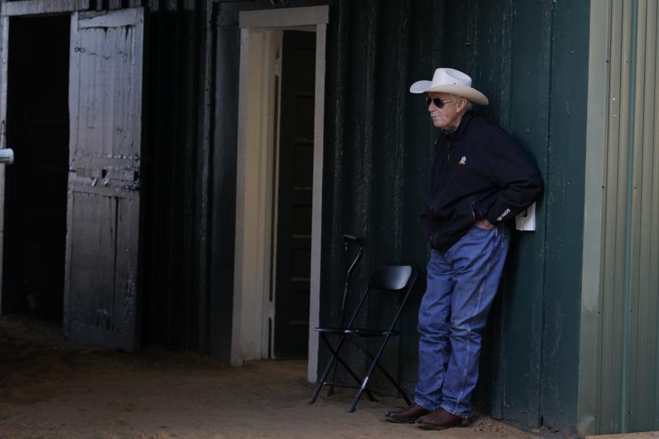 Horse trainer D. Wayne Lukas stands at the stables after Preakness entrant Secret Oath worked out