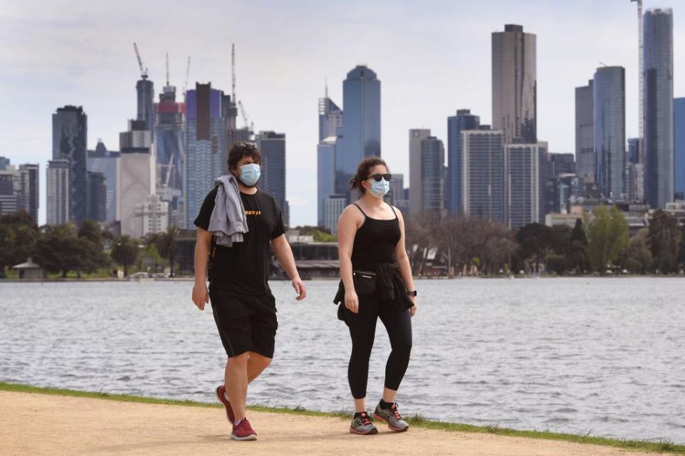 Pictured are two people in Melbourne wearing face masks.