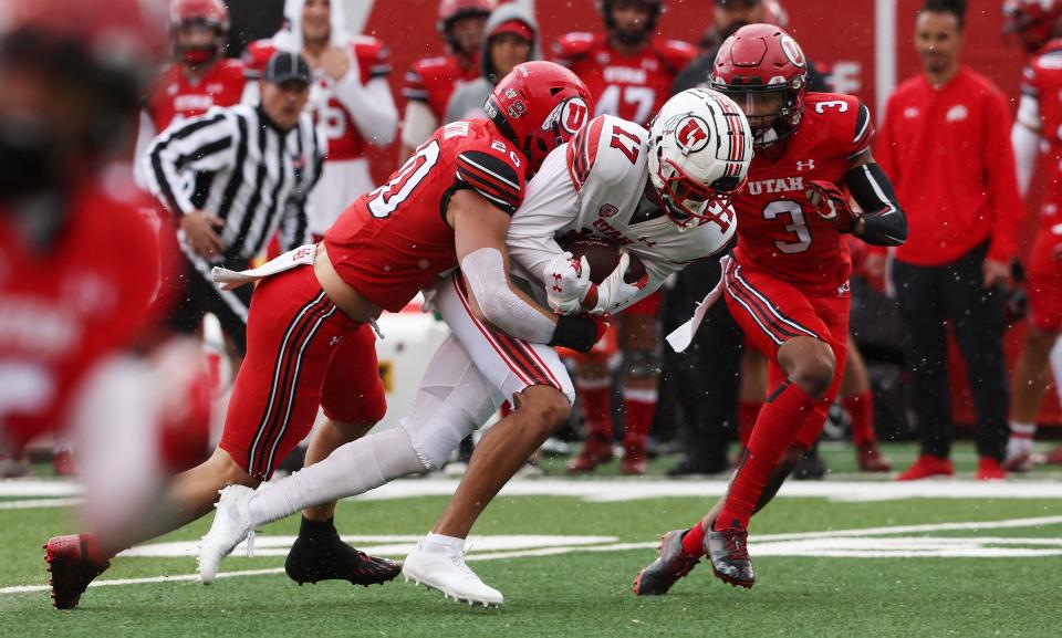 The White team’s Devaughn Vele is tackled by the Red team’s Lander Barton during Red and White Game in Salt Lake City.