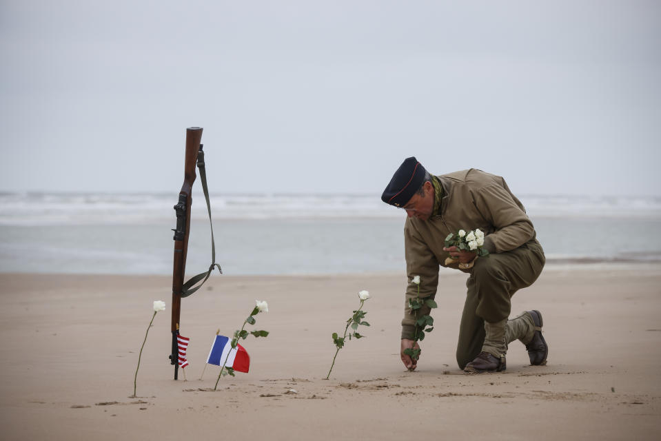 FILE - A World War II reenactor plants roses on Omaha Beach in Saint-Laurent-sur-Mer, Normandy, France, June 6, 2023. France is getting ready to show its gratitude towards World War II veterans who will come, many for the last time, on Normandy beaches for D-Day ceremonies that will come as part of a series of major commemorations this year and next marking eight decades since the defeat of the Nazis. (AP Photo/Thomas Padilla, File)