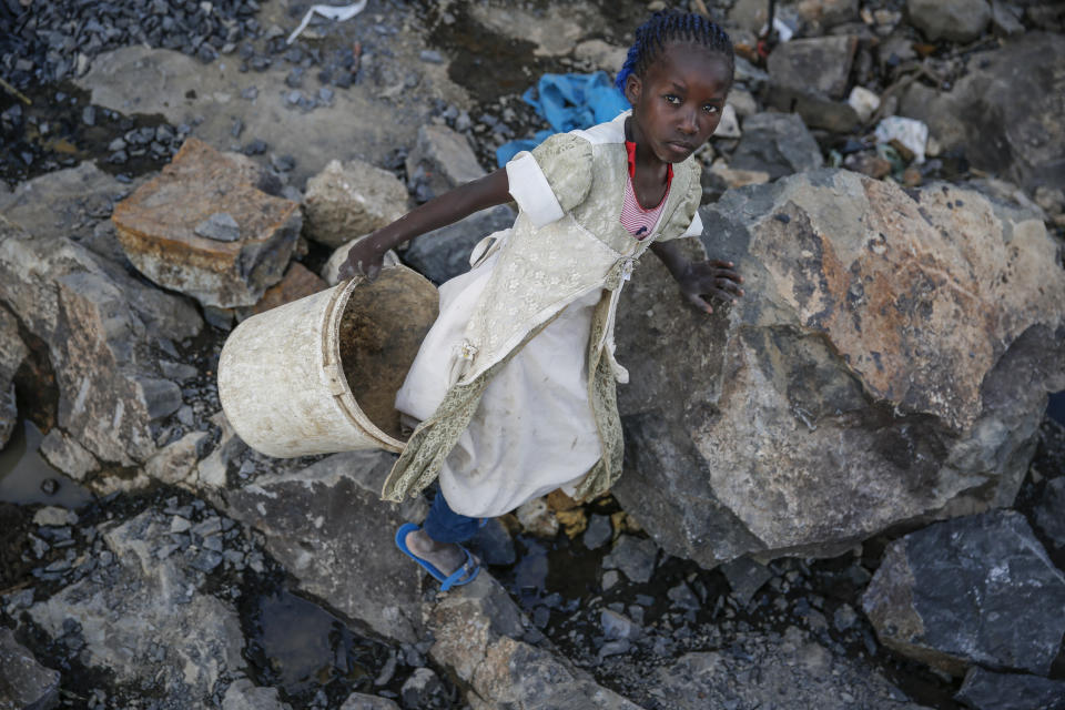 Irene Wanzila, 10, carries a bucket of broken rocks after breaking them with a hammer along with her younger brother, older sister and mother, who says she was left without a choice after she lost her cleaning job at a private school when coronavirus pandemic restrictions were imposed, at Kayole quarry in Nairobi, Kenya Tuesday, Sept. 29, 2020. The United Nations says the COVID-19 pandemic risks significantly reducing gains made in the fight against child labor, putting millions of children at risk of being forced into exploitative and hazardous jobs, and school closures could exacerbate the problem. (AP Photo/Brian Inganga)