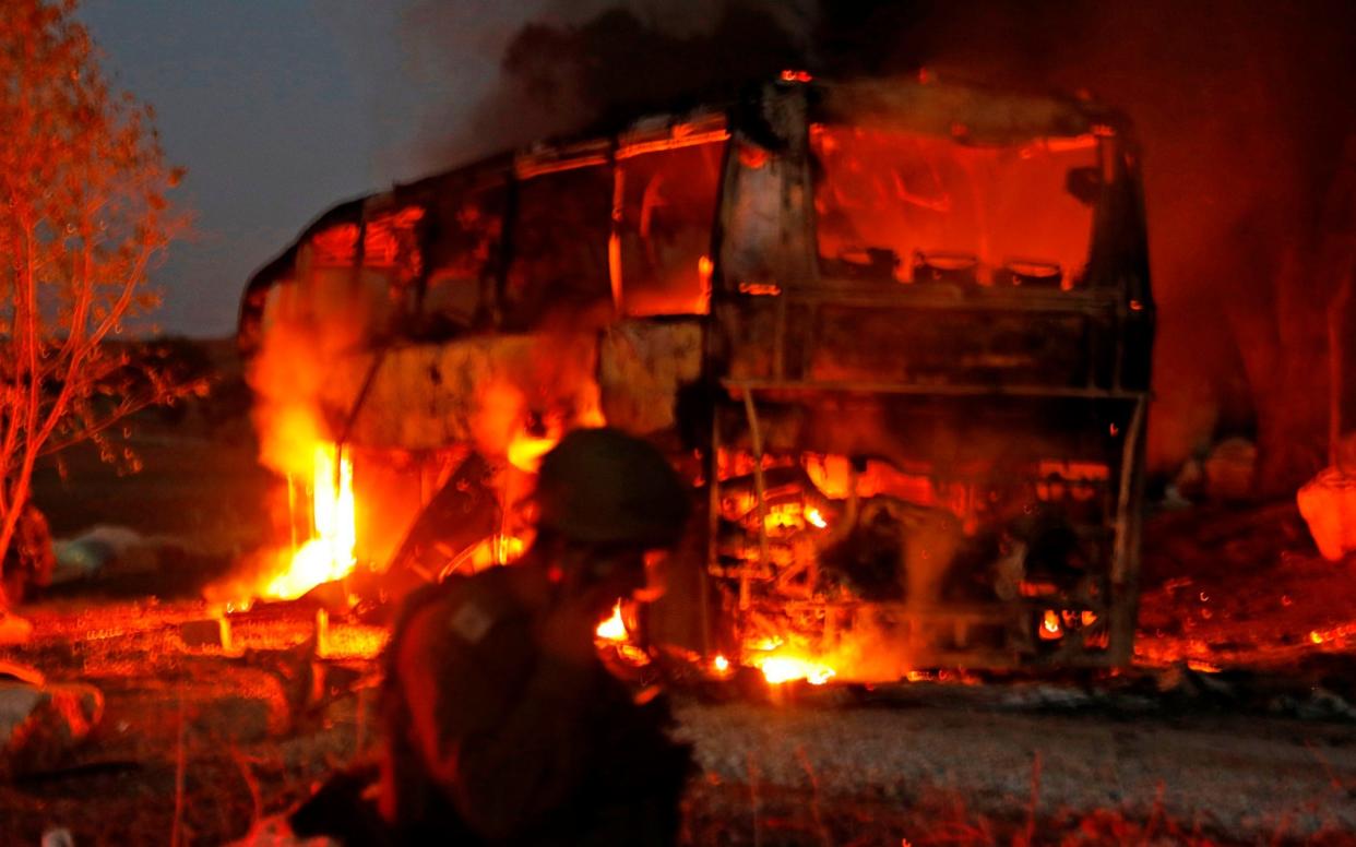 Israeli security forces and firefighters gather near a bus set ablaze after it was hit by a rocket fired from the Palestinian enclave - AFP