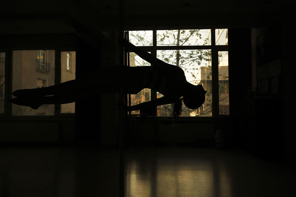 In this Thursday, April 30, 2020 photo, Tuba Parlak, 39, a pole dancing performer and instructor warms-up at her studio in Istanbul, as she prepares for an online training session for students at home, due to the coronavirus restrictions. To stem the spread of COVID-19, Turkey closed down sports facilities in March but Parlak's students wanted to continue their pole lessons. Using video conferencing, Parlak teaches the vigorous exercise from her studio in Istanbul's hip Cihangir district. (AP Photo/Emrah Gurel)