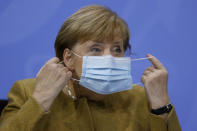 German Chancellor Angela Merkel takes off her face mask as she arrives for a press conference following talks via video conference with Germany's state governors on extending coronavirus restrictions at the Chancellery in Berlin, Wednesday, Nov. 25, 2020. Merkel and the country’s 16 state governors have agreed to extend a partial shutdown well into December in an effort to further reduce the rate of coronavirus infections ahead of the Christmas period. Germany embarked on a so-called “wave-breaker” shutdown on Nov. 2, initially slated to last four weeks. (Odd Andersen/Pool Photo via AP)