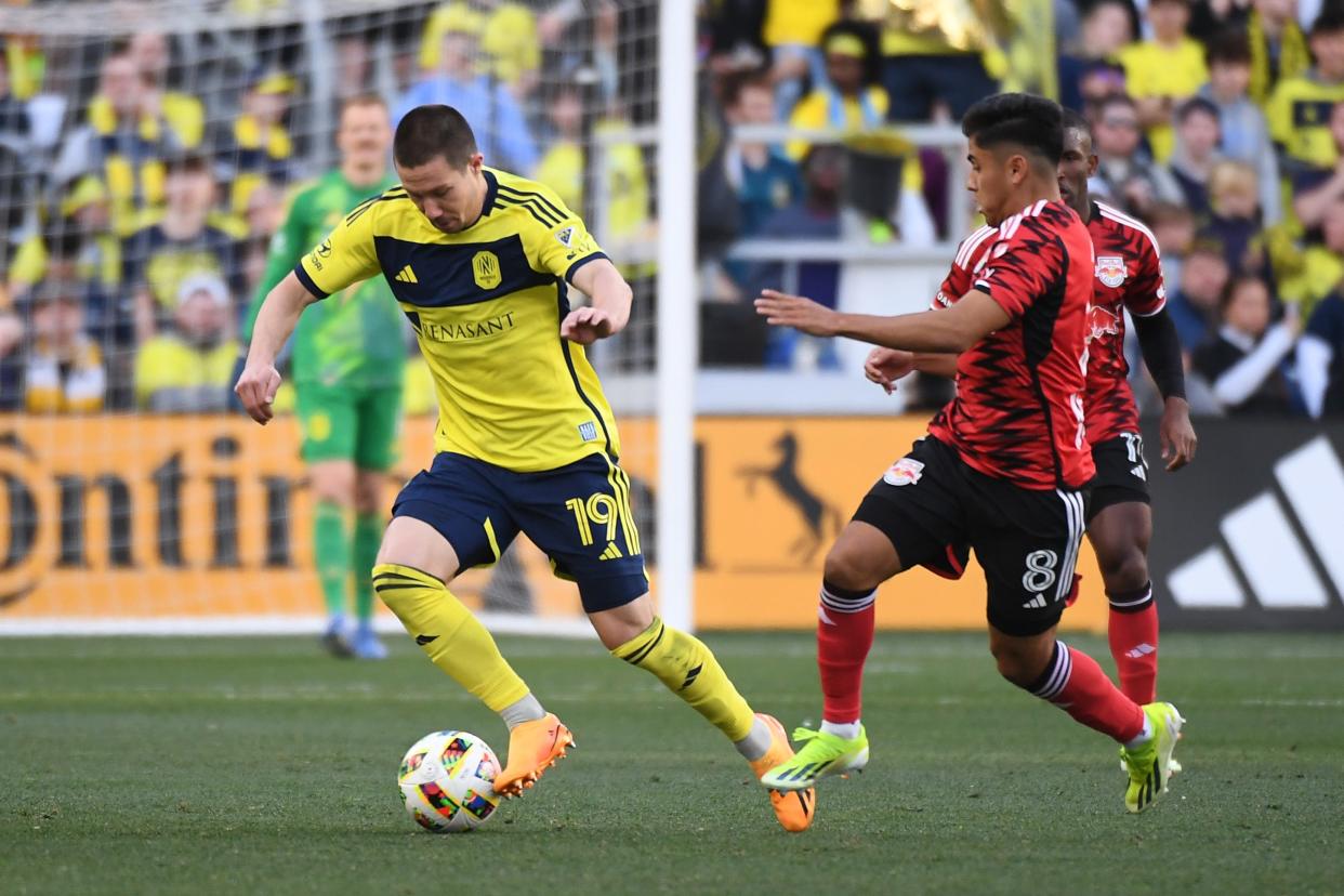 Feb 25, 2024; Nashville, Tennessee, USA; Nashville SC midfielder Alex Muyl (19) dribbles the ball against New York Red Bulls midfielder Frankie Amaya (8) during the first half at Geodis Park. Mandatory Credit: Christopher Hanewinckel-USA TODAY Sports