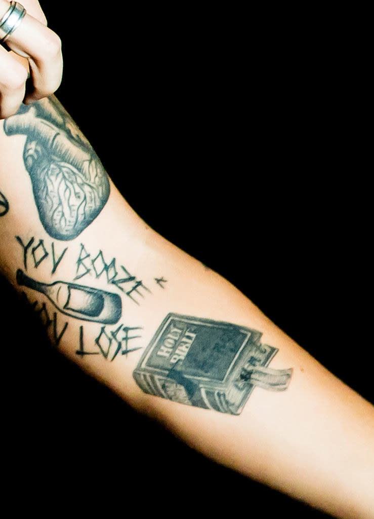 A tat of the "Holy Bible" along with other tats on his arm