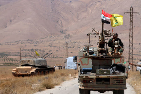 FILE PHOTO: Hezbollah and Syrian flags flutter on a military vehicle in Western Qalamoun, Syria August 28, 2017. REUTERS/Omar Sanadiki/File Photo