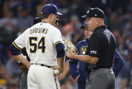 Umpire Jeff Nelson inspects the glove of Milwaukee Brewers pitcher Jake Cousins during the seventh inning of a baseball game against the St. Louis Cardinals, Thursday, Sept. 23, 2021, in Milwaukee. The glove was removed from the game. (AP Photo/Jeffrey Phelps)