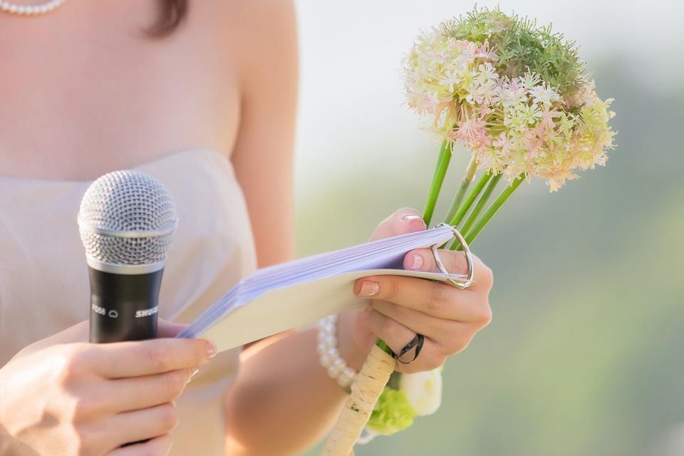 <p>NUTCHAPONG WUTTISAK/Getty</p> A bouquet of flowers in the hands of a female host, holding a microphone, waiting for the schedule to report the order of the event