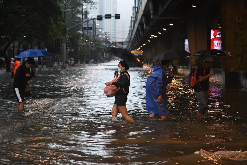 Pedestrians cross a flooded street in Manila amid heavy rains brought by Typhoon Gaemi. (AFP via Getty Images)