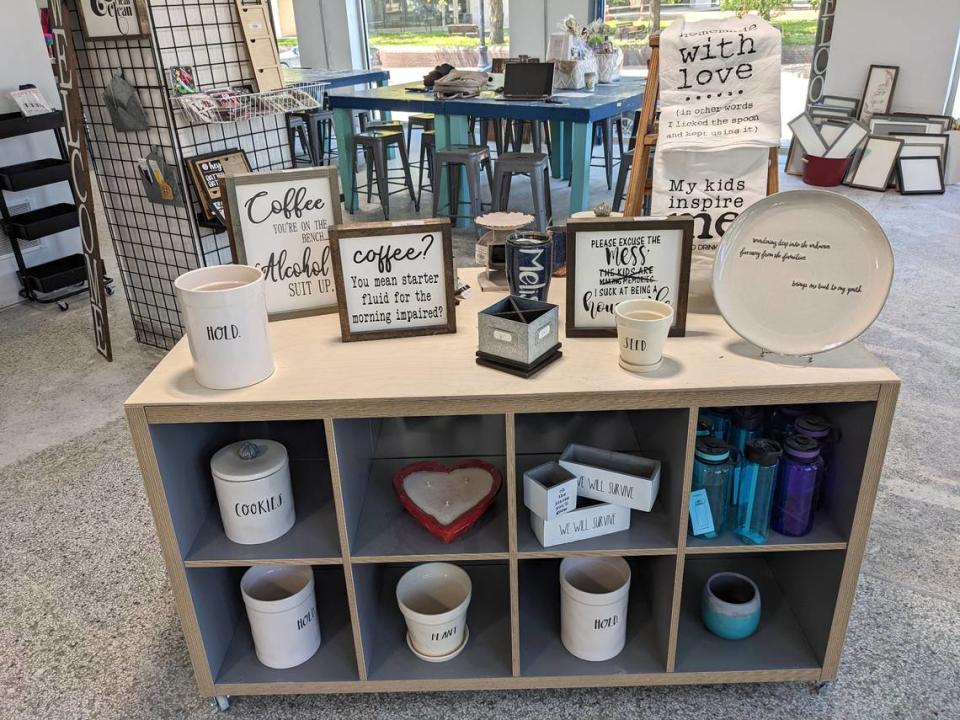 A display of planters, coffee-themed signs and other items with a peek at the classroom studio area in the background at Sawdust & Glitter in Belleville