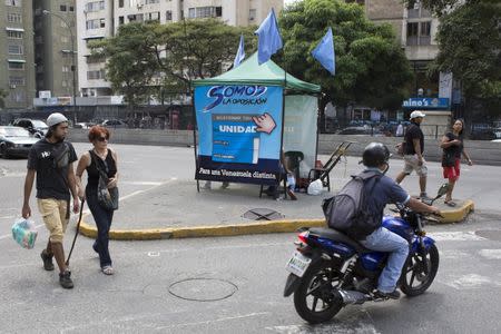 People pass by a tent for MIN Unidad Party in a main avenue in Caracas, November 3, 2015. REUTERS/Marco Bello