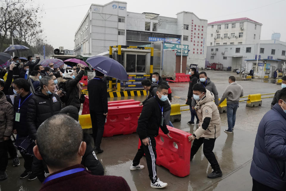 Security personnel use barriers to block the way after the World Health Organization team arrive at the Baishazhou wholesale market on the third day of field visit in Wuhan in central China's Hubei province on Sunday, Jan. 31, 2021. (AP Photo/Ng Han Guan)