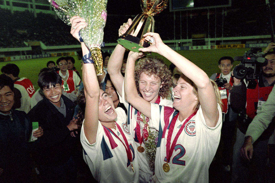 Michelle Akers-Stahl, who scored two goals for the U.S. to win what would be the first FIFA Women’s World Cup on Nov. 30, 1991, holds the trophy with teammates Julie Foudy, left, and Carin Jennings, right.