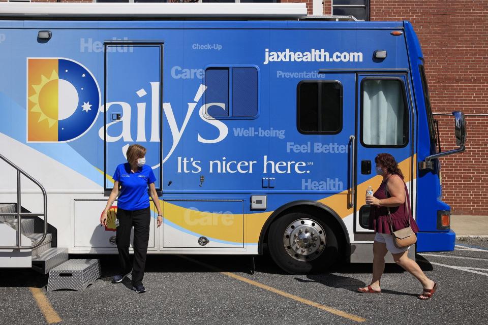 At Lakeshore Baptist Church in Jacksonville, registered nurse Claudia Portell (left) greets patient Victoria Nelson outside an Ascension St. Vincent's mobile health care clinic for a checkup.