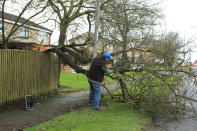 A man works to remove a tree blown over by Storm Dennis in Birkenshaw on the outskirts of Bradford, Leeds. (PA)