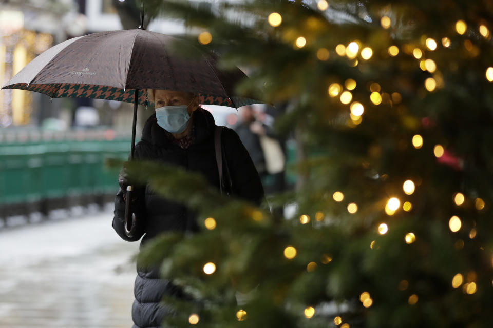 A pedestrian passes Christmas decorations of a closed shop in Oxford Street in London, Wednesday, Dec. 23, 2020. Britain's Prime Minister Boris Johnson imposed a new, higher level of coronavirus restrictions to curb sharply spreading infections in the capital and other areas. (AP Photo/Kirsty Wigglesworth)