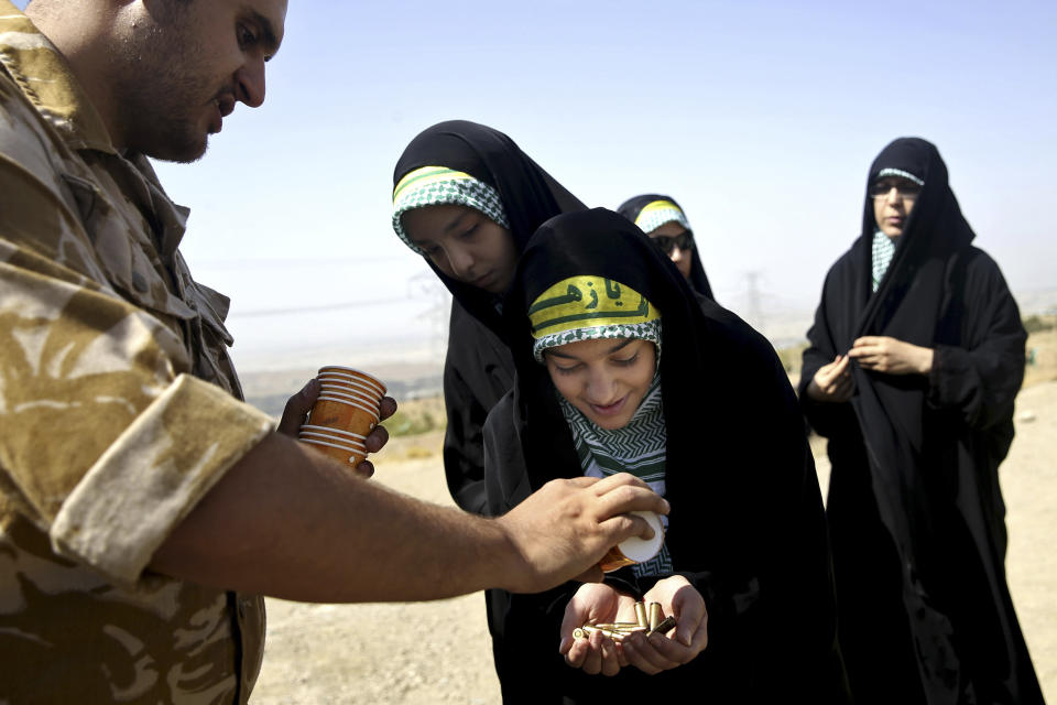 FILE-- In this Aug. 22, 2013 file photo, a female member of the Iranian Basij paramilitary militia, affiliated to the Revolutionary Guard, receives bullets during a training session in Tehran, Iran. On Monday, April 8, 2019, the Trump administration designated Iran’s Revolutionary Guard a “foreign terrorist organization” in an unprecedented move against a national armed force. Iran’s Revolutionary Guard Corps went from being a domestic security force with origins in the 1979 Islamic Revolution to a transnational fighting force. (AP Photo/Ebrahim Noroozi, File)