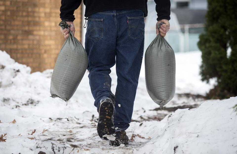 Larry Miceli carries sandbags as he prepares his house for possible flooding following a massive snow storm in West Seneca