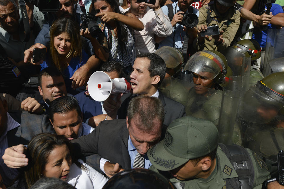 Opposition leader Juan Guaido yells into a megaphone for National Guards to let him and all opposition lawmakers into the National Assembly, outside the legislature in Caracas, Venezuela, Tuesday, Jan. 7, 2020. Guaidó and lawmakers who back him pushed their way into the legislative building on Tuesday following an attempt by rival legislators to take control of the congress, and declared Guaidó the president of the only opposition-controlled institution. (AP Photo/Matias Delacroix)