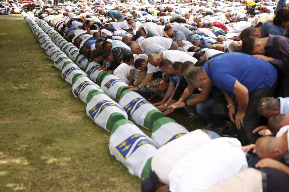 Bosnian muslim men pray next to the coffins containing the remains of 50 newly identified victims of the Srebrenica Genocide, in Potocari, Monday, July 11, 2022. Fifty newly identified victims were honored and reburied Monday in Bosnia as thousands gathered to commemorate the anniversary of the 1995 Srebrenica massacre, Europe’s only acknowledged genocide since the Holocaust. (AP Photo/Armin Durgut)