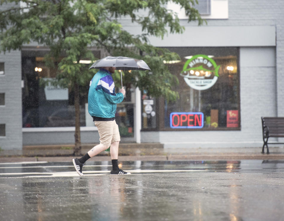 A pedestrian walks with an umbrella along King Street in Fredericton, N.B. on Saturday, Sept. 16, 2023. Severe conditions were predicted across parts of Massachusetts and Maine, and hurricane conditions could hit the Canadian provinces of New Brunswick and Nova Scotia, where the storm, Lee, downgraded early Saturday from hurricane to post-tropical cyclone, was expected to make landfall later in the day. (Stephen MacGillivray /The Canadian Press via AP)