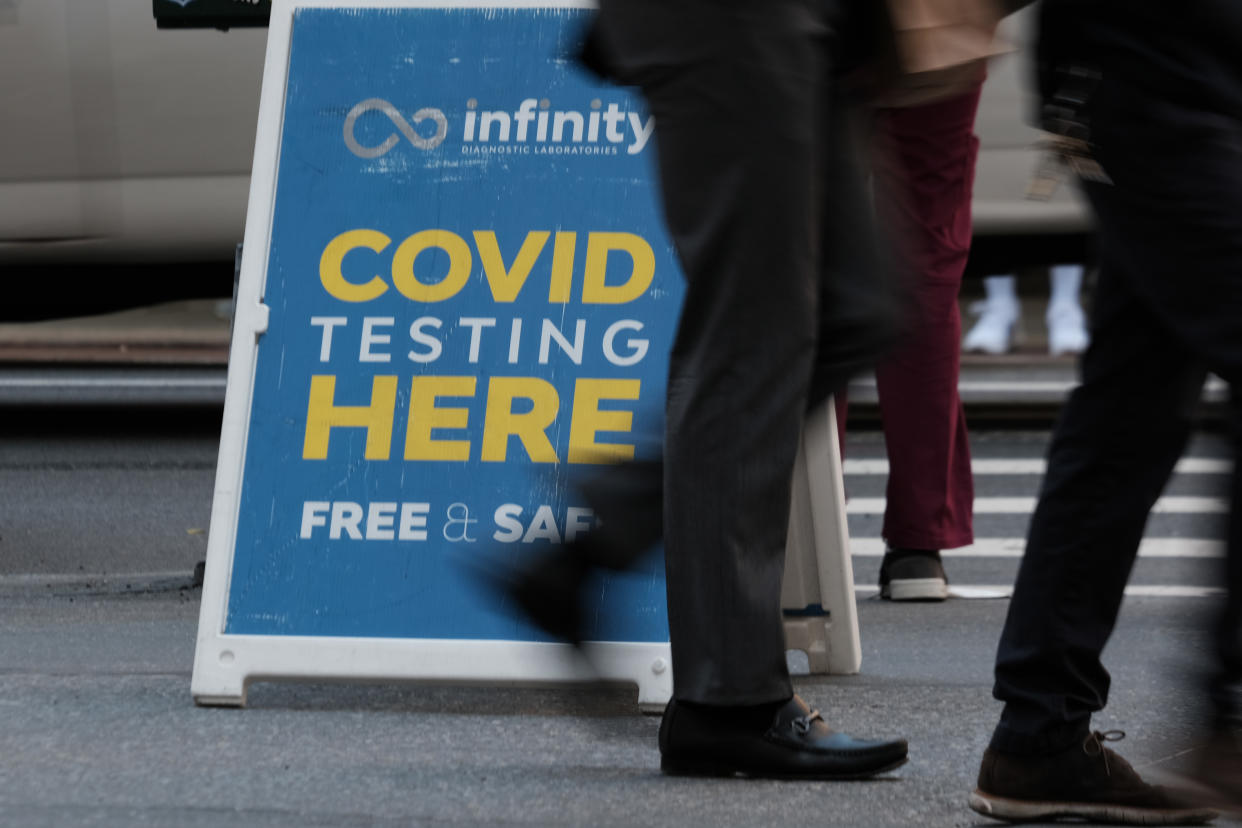 People walk past a notice saying: Infinity, COVID testing here. Free & Safe.