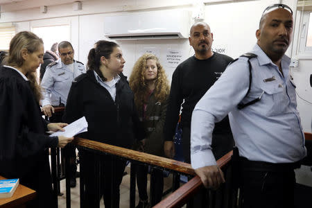 Palestinian teen Ahed Tamimi enters a military courtroom escorted by Israeli security personnel as her lawyer Gaby Lasky (L) stands near, at Ofer Prison, near the West Bank city of Ramallah, February 13, 2018. REUTERS/Ammar Awad