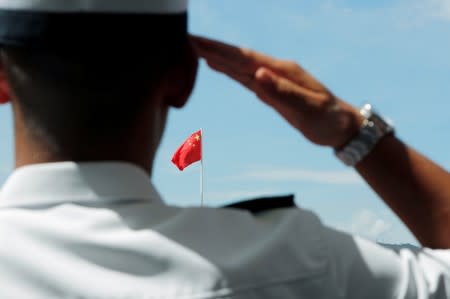 FILE PHOTO: A People's Liberation Army (PLA) soldier salutes the Chinese national flag during an open day at Stonecutters Island naval base in Hong Kong