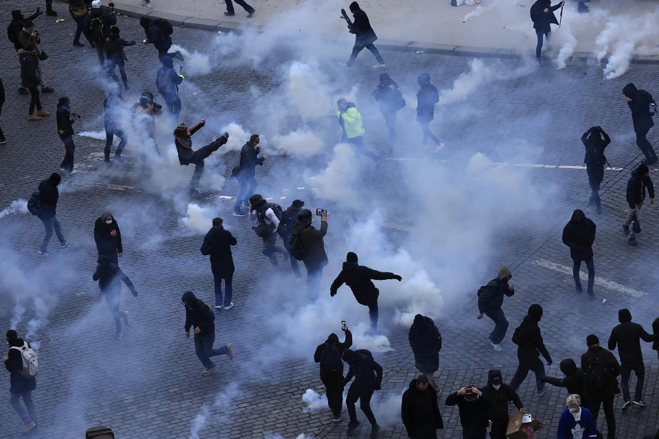 Youths kick tear gas canisters during a demonstration in Paris, Tuesday, March 7, 2023. Hundreds of thousands of demonstrators across France took part Tuesday in a new round of protests and strikes against the government's plan to raise the retirement age to 64, in what unions hope will be their biggest show of force against the proposal. (AP Photo/Aurelien Morissard)