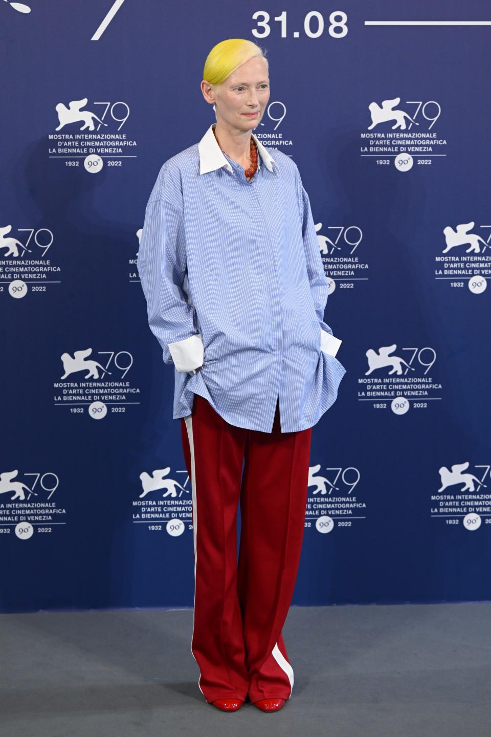 Tilda Swinton in a blue shirt and red pants