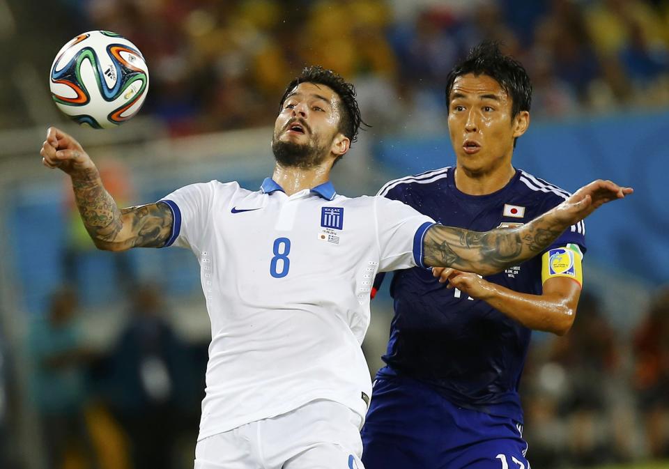 Greece's Panagiotis Kone (L) fights for the ball with Japan's Makoto Hasebe during their 2014 World Cup Group C soccer match at the Dunas arena in Natal June 19, 2014. REUTERS/Kai Pfaffenbach