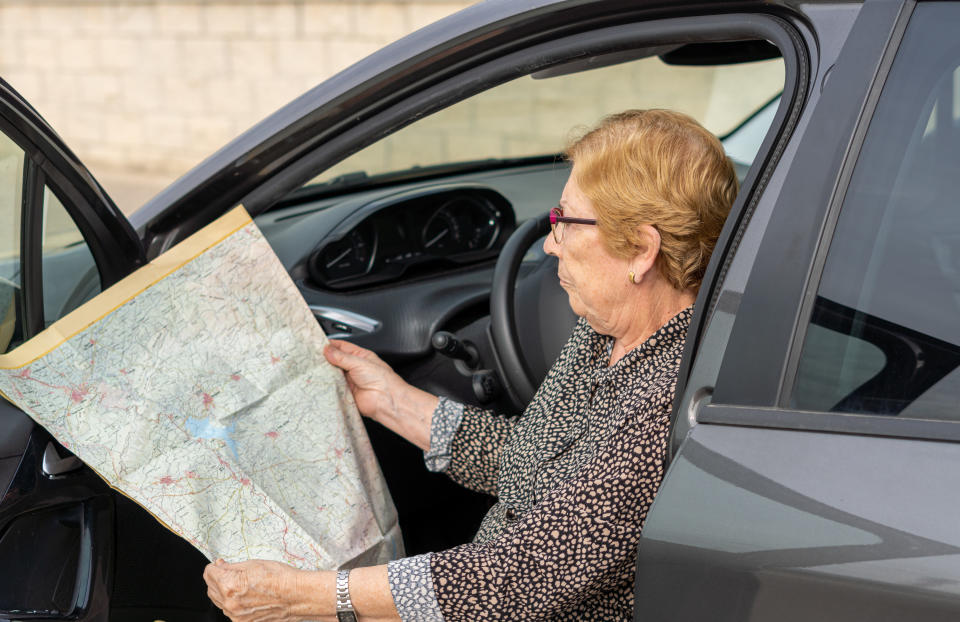 pessoa sentada no carro estacionado, olhando para um mapa rodoviário