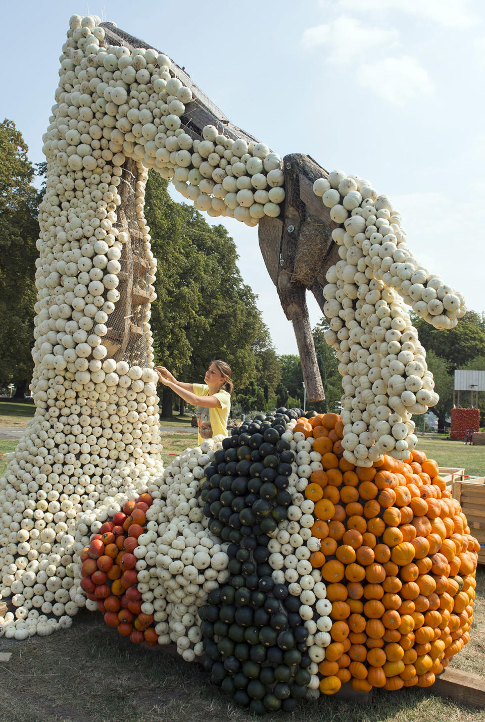 A helper works behind a swimmer sculpture during the preparations of the autumn pumpkins exhibition