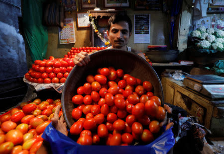 A vendor loads tomatoes in a bag for a customer at a wholesale vegetable market in Mumbai, India, March 14, 2018. REUTERS/Danish Siddiqui