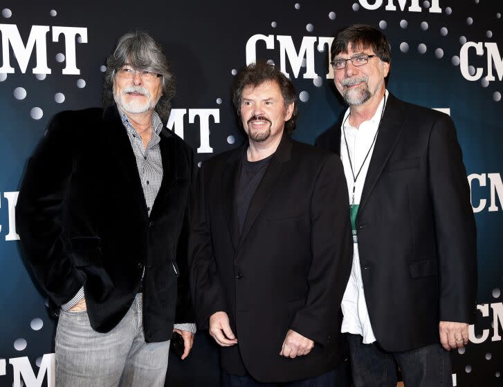 Three men from musical group Alabama standing in front of CMT red carpet banner