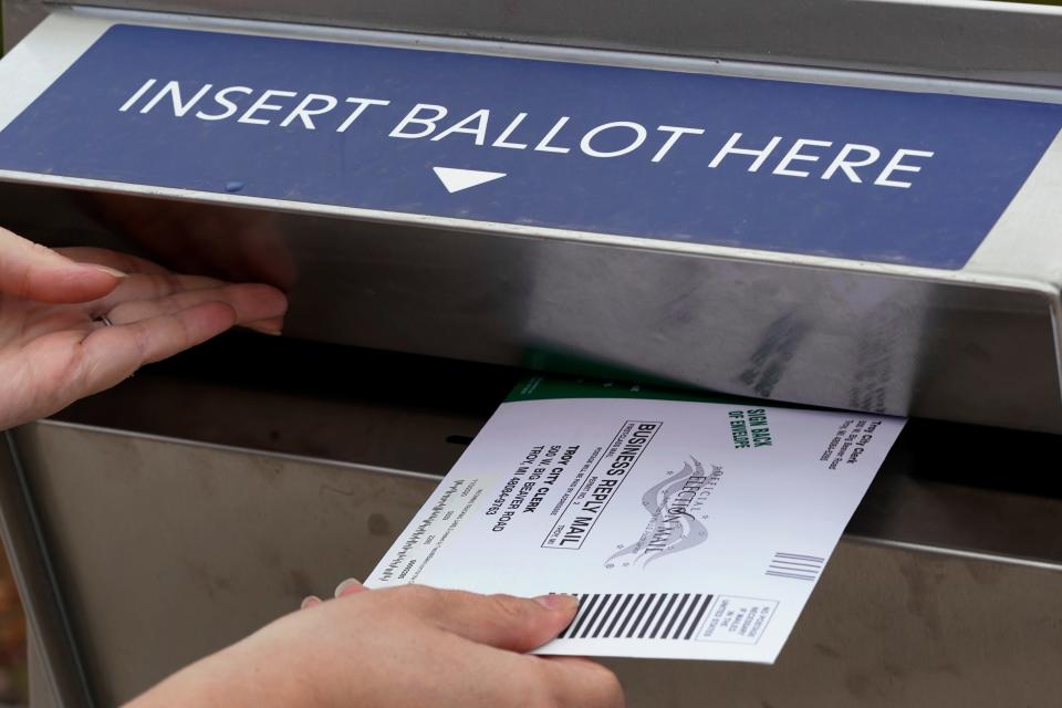 A Michigan voter inserts her absentee voter ballot into a drop box in Troy, Mich., on Oct. 15, 2020.